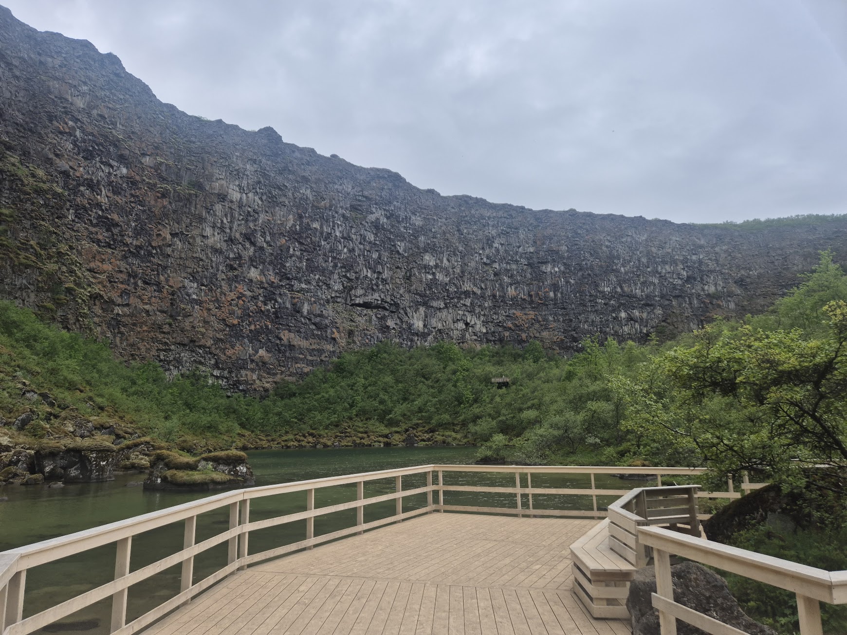 Wooden viewing platform at the end of Ásbyrgi canyon below the tall basalt wall