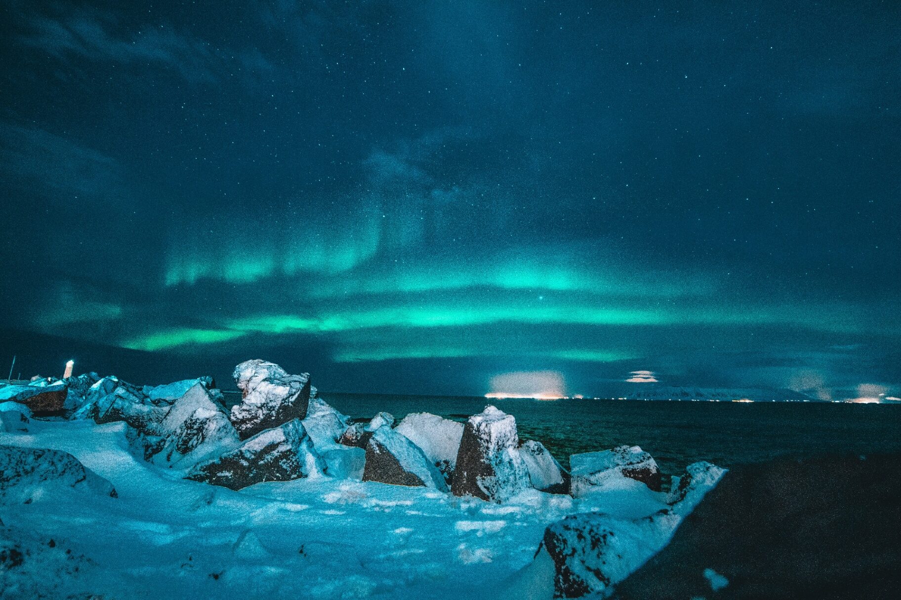 Northern lights above a snowy Iceland coastline in winter