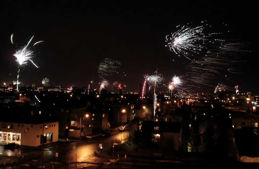 Fireworks bursting over Reykjavík rooftops and lit streets on New Year's night